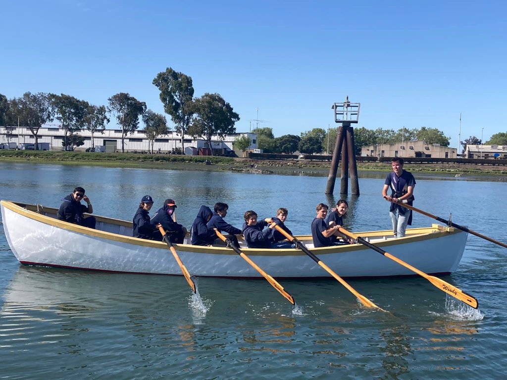 Group of Sea Scout Ship Corsair members rowing in a whaleboat looking at the camera
